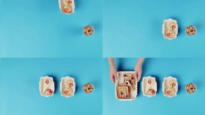 送餐顶视图，在蓝色背景上的一次性容器中带走甜点。午餐盒配有煮熟的芝士蛋糕、比利时华夫饼。餐饮糖果服务