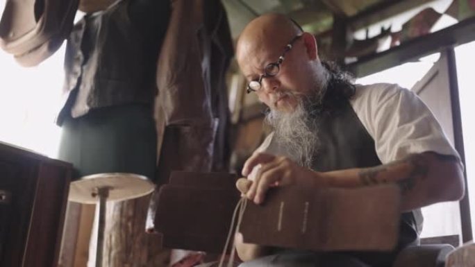男人精心手工缝制皮革产品。