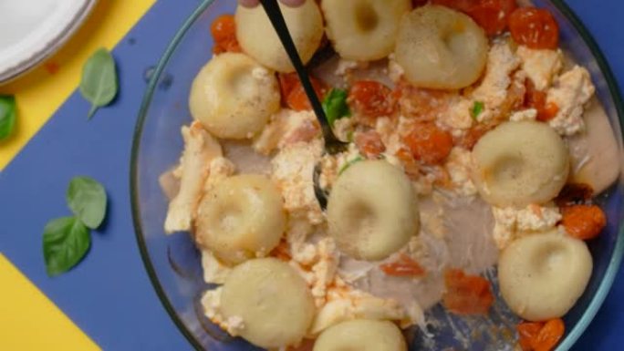 垂直桌面视频: 厨师用勺子用西红柿和羊乳酪煮熟的土豆饺子