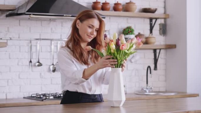 红色长发的成年女性拿着带花的花瓶