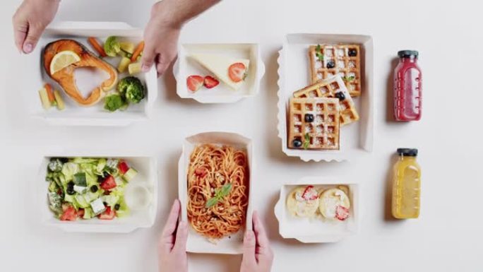 送餐俯视图，在白色背景上的一次性容器中带走餐点。把饭盒放炸鱼和意大利肉酱。健康饮食。餐饮服务理念。