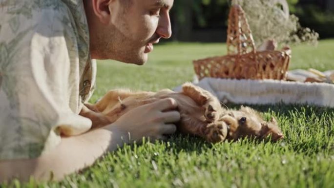 玩小狗快乐的男孩躺在绿草地上玩狗可卡犬野餐动物的爱