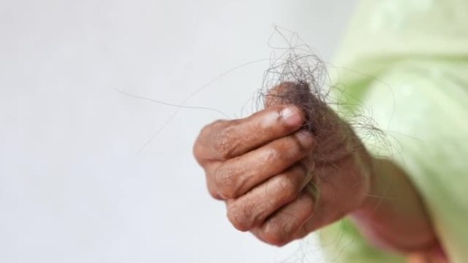 高级女性手握一把白底脱发的刷子