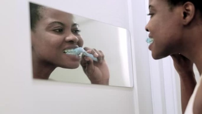 肖像快乐黑人非洲裔美国女孩在浴室刷牙。早上用牙刷照镜子的女人