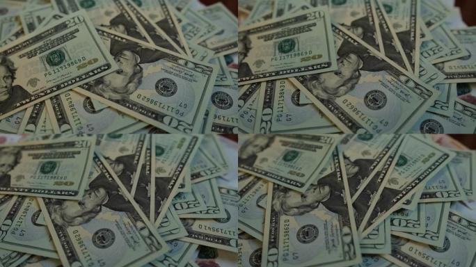 二十美元的钞票落在桌子上，上面有一叠旋转的钱，特写。