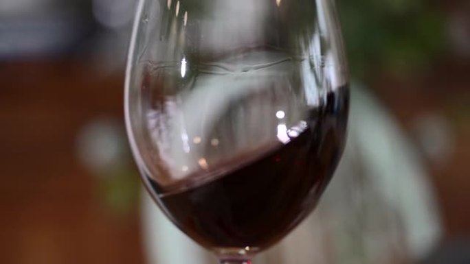 一杯红酒。在餐厅或酒吧的木桌背景上的玻璃杯中倒酒。味道，香气，丰富。葡萄收获概念的酒精饮料。