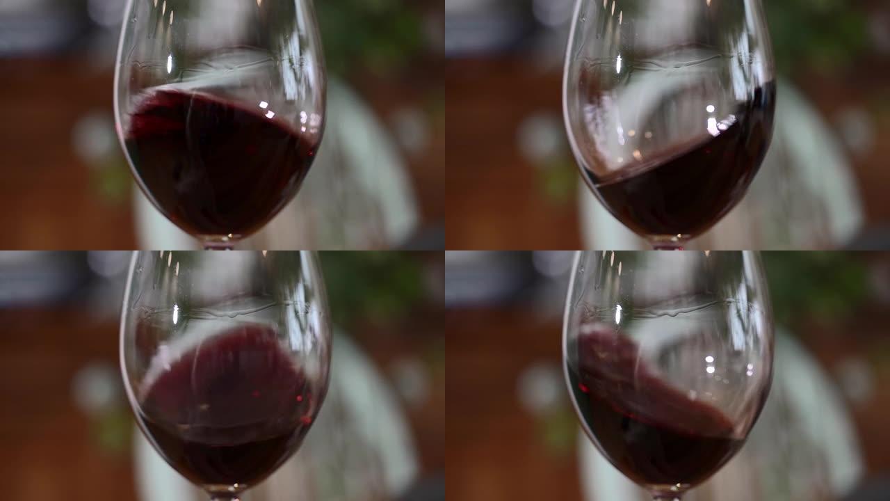 一杯红酒。在餐厅或酒吧的木桌背景上的玻璃杯中倒酒。味道，香气，丰富。葡萄收获概念的酒精饮料。