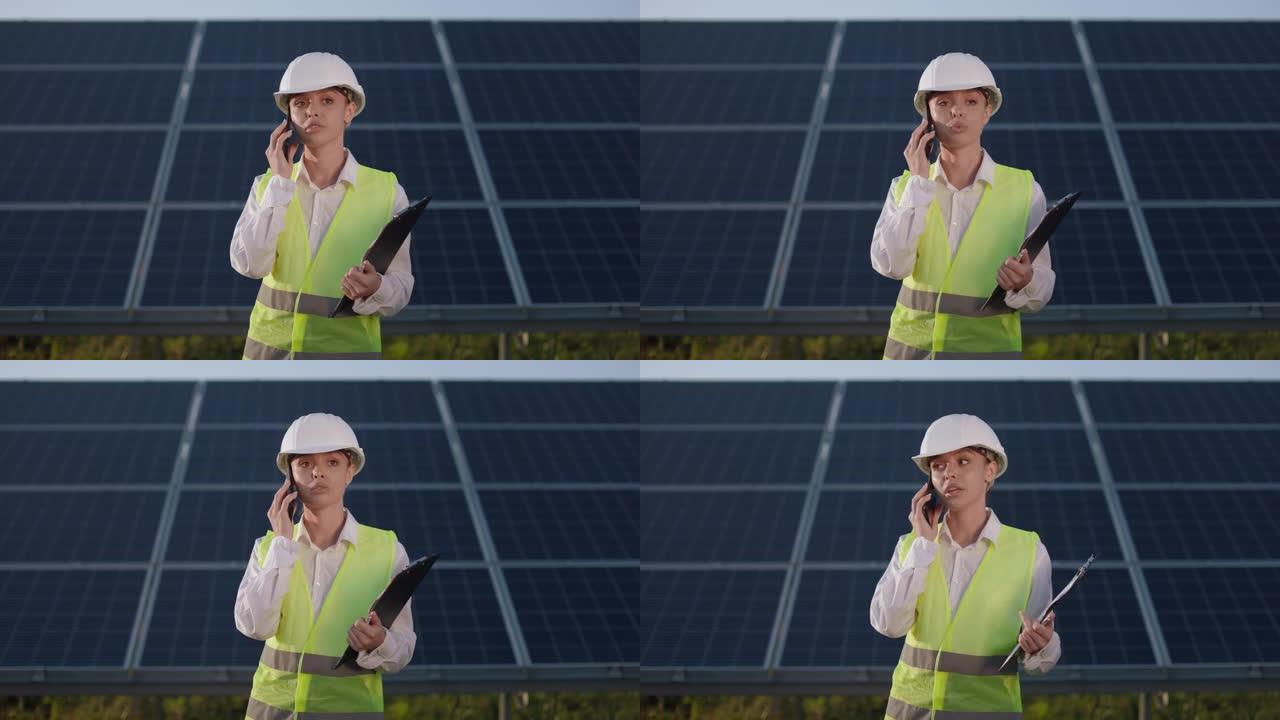 戴头盔的女人在太阳能农场之间进行移动交谈。