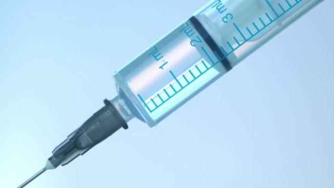 注射器蓝色背景下注射液体的特写。药物药物针头注射器流感疫苗小瓶剂量皮下注射治疗疾病预防预防接种。