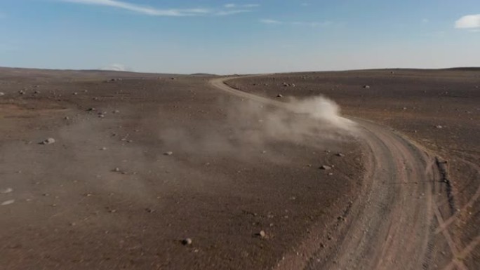汽车在土路上行驶，扬起尘土。晴天北欧火山景观有大风天气。冰岛