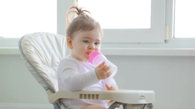 可爱的女婴在房子窗户附近玩塑料勺子。