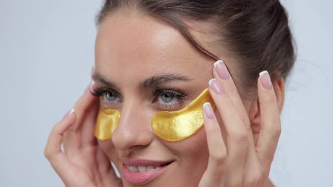 女人在加里背景上性感地在相机上摆出金色眼罩的特写镜头。美概念。