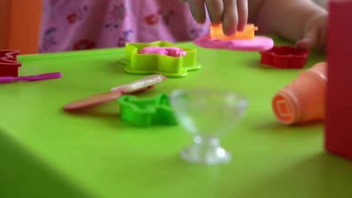 儿童雕塑和泥塑造型。2-5岁的女孩通过手指和塑料造型刀形成和塑造粉红色的面团。使用黏土增强精细运动技