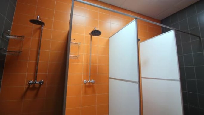 带新设备和橙色瓷砖墙的空淋浴房