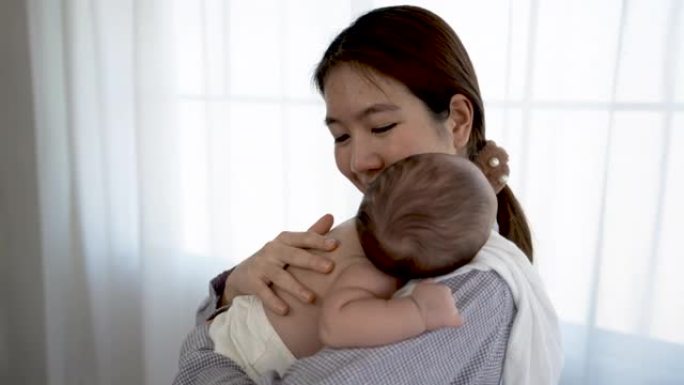 4K 25fps慢动作，母亲抱着婴儿并揉了揉头，使她在温暖的怀抱中入睡。