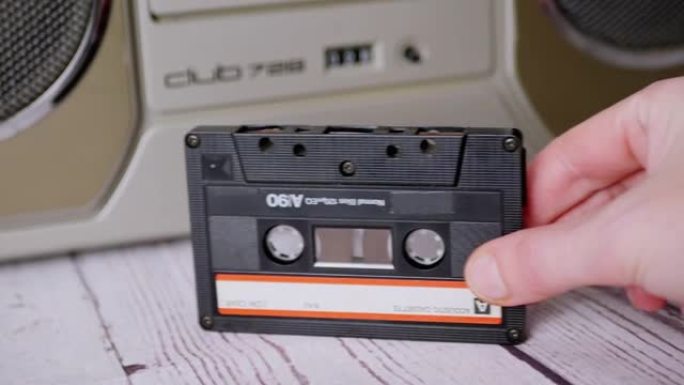 女性手在立体声录音机附近握住90年代的旧录音带