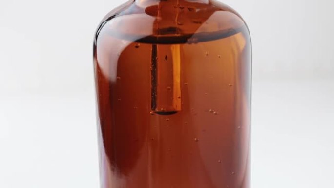 玻璃棕色精油瓶的特写镜头，气泡在其中移动并上升到顶部。