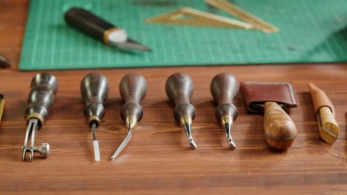 工匠的工具特写。工作场所餐桌上的人造革刀具、设备、真皮动物皮革手工制品。专业工作室。