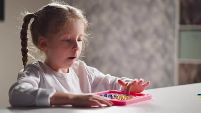 受启发的小女孩学会在桌子上用玩具算盘计数
