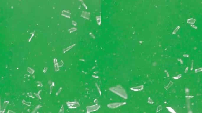 玻璃破碎和破碎的碎片在绿色背景上飞过。色度键。