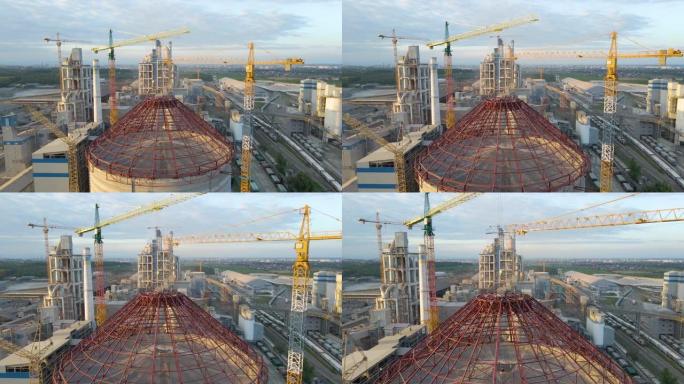 工业生产区高混凝土厂房结构和塔式起重机在建水泥厂的鸟瞰图。制造业和全球工业概念。