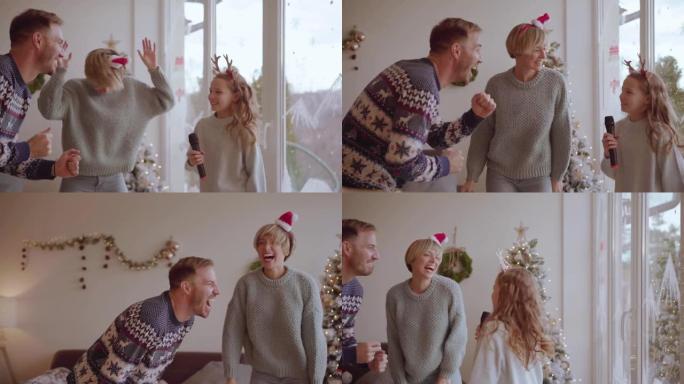 美丽的年轻家庭在客厅里跳舞和唱歌的圣诞节传统