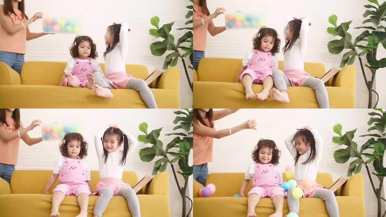 亚洲妈妈和孩子一起在沙发上玩球和玩具