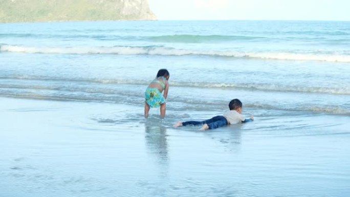 哥哥和蹒跚学步的妹妹在海滩玩水。