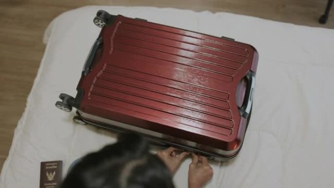 女性游客重新检查她的手提箱是否已锁定，准备在周末旅行。