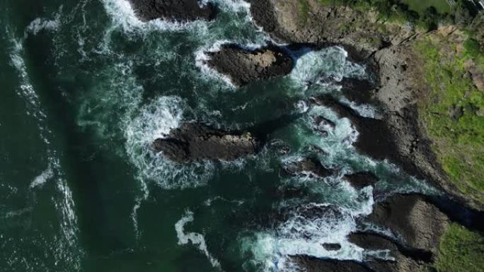 海浪冲破沿海岬角上高耸的火山岩壁架。无人机视图
