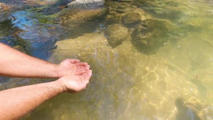 晴天双手从瀑布中捞水的视频。用手接水。清澈的溪流。与家人一起享受大自然，旅行，瀑布之旅