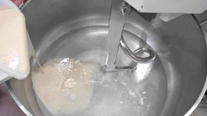 面包师将酵母倒入面包厂的大型面团搅拌机中。高质量4k镜头