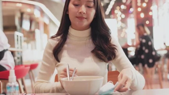 亚洲妇女分开坐在餐馆吃饭。保持社交距离，以保护感染免受冠状病毒新型冠状病毒肺炎，餐厅和社交距离概念的