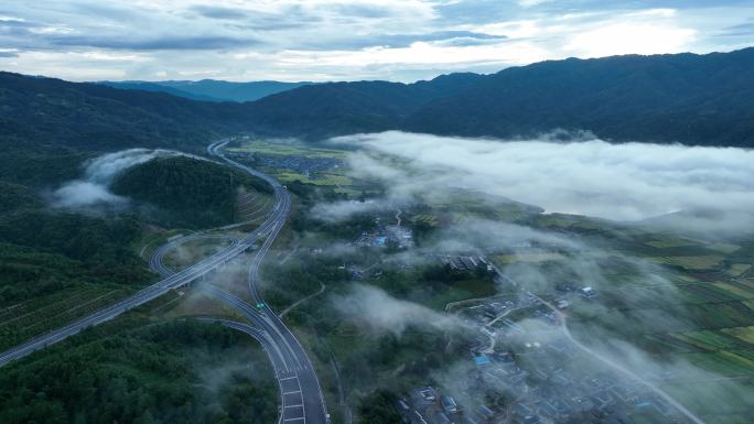 高速公路穿过晨雾弥漫的山村稻田