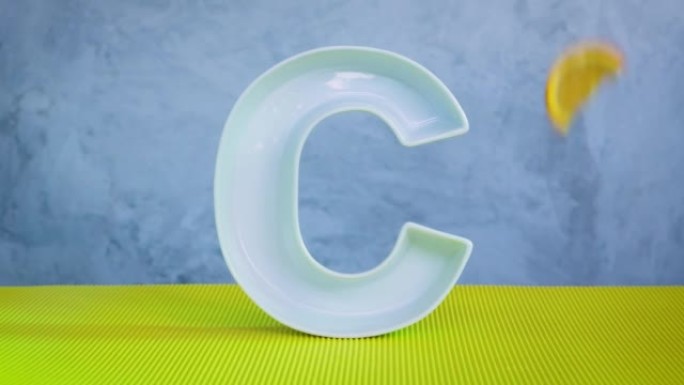 食品概念中的维生素c。大陶瓷字母C和新鲜的橙色切片落在灰色和黄色背景上。抗坏血酸对免疫系统功能很重要