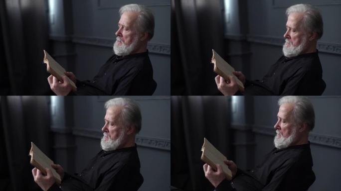 在黑暗的图书馆里，有思想的白发老人在阅读旧纸质书的跟踪镜头。