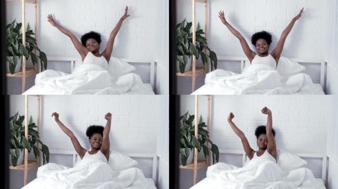 懒惰的早晨，穿着睡衣的年轻黑人女孩在床上伸展，在卧室里小睡