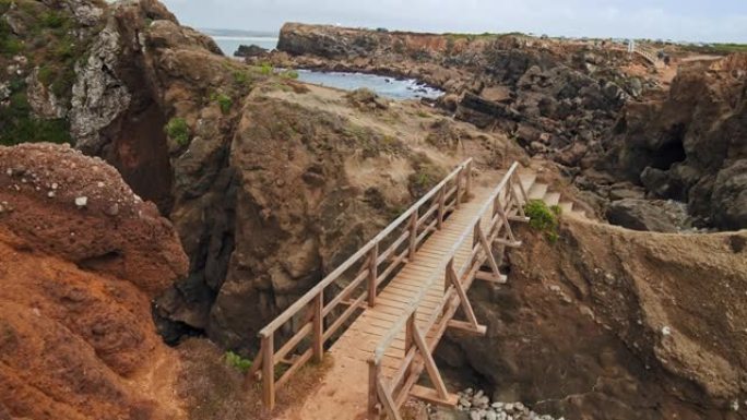 一座木桥以4k的方式连接着海边岩石悬崖的两侧。