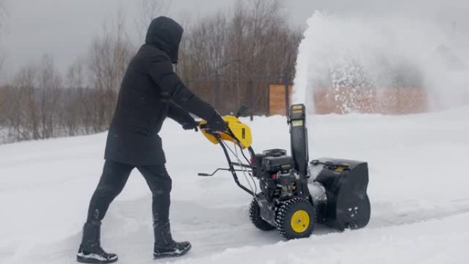 大雪过后，男人用木屋的扫雪机清理积雪。扫雪机在工作。慢动作