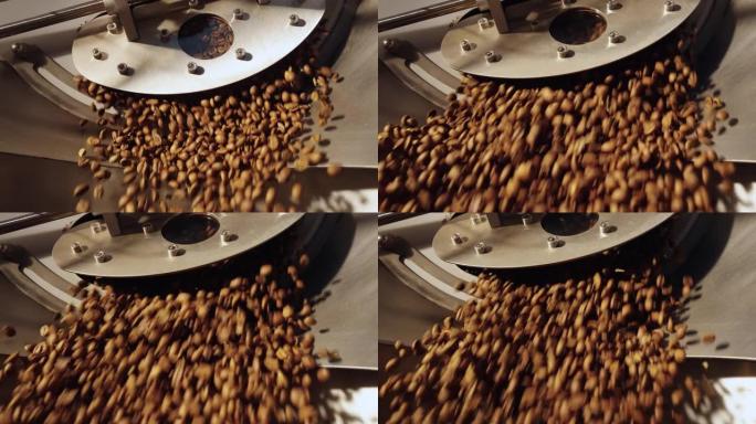 将芬芳的烘焙咖啡豆倒入工厂的工业混合和冷却机中。生产新鲜烘焙的咖啡豆。咖啡馆的餐饮背景。特写，慢动作