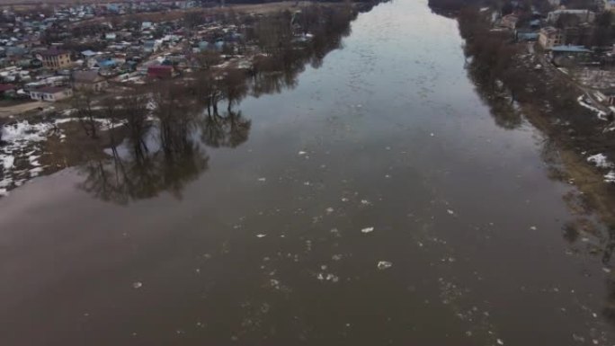 肮脏的白色浮冰漂浮在泥泞的河上。
