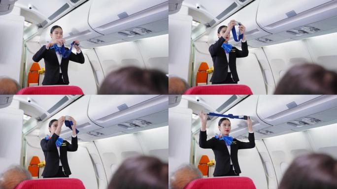 穿着制服的美丽的亚洲空姐向机舱，飞机上的乘客展示了如何在飞行中使用安全带和其他安全措施