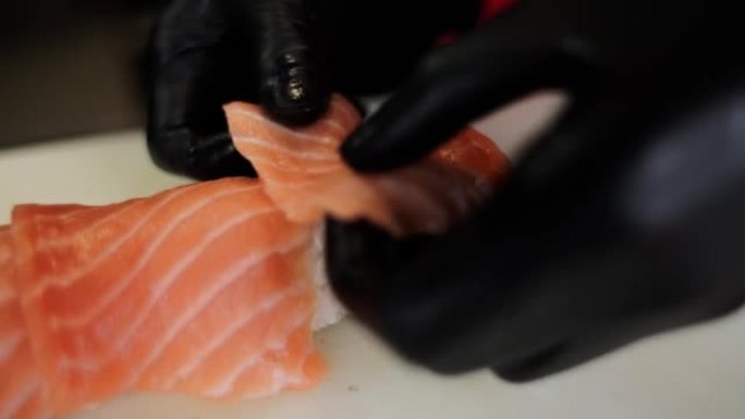 男厨师将红鲑鱼放在日本寿司卷上
