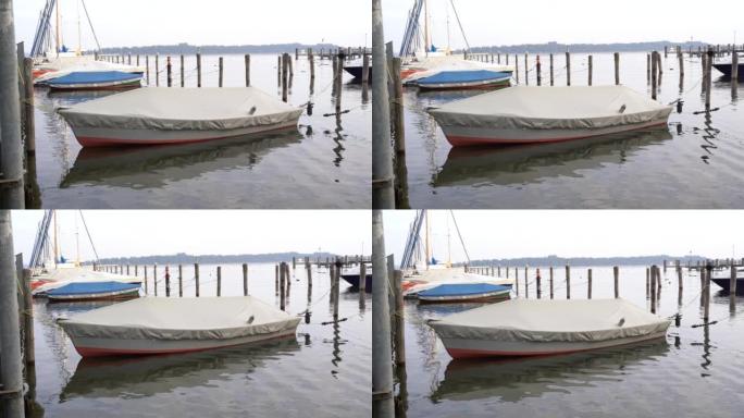 一艘被覆盖并绑在木柱上的船早上漂浮在湖中