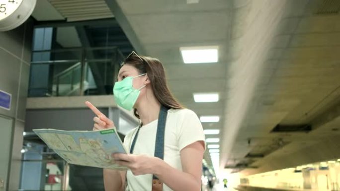戴着口罩的亚洲女性游客在火车站搜索位置图。