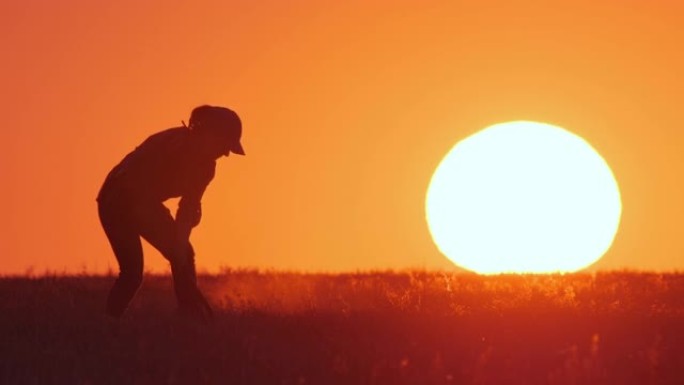 穿着橡胶靴的农民或园丁的剪影用铲子挖地，背景是橙色的日落天空与大太阳