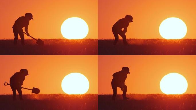 穿着橡胶靴的农民或园丁的剪影用铲子挖地，背景是橙色的日落天空与大太阳