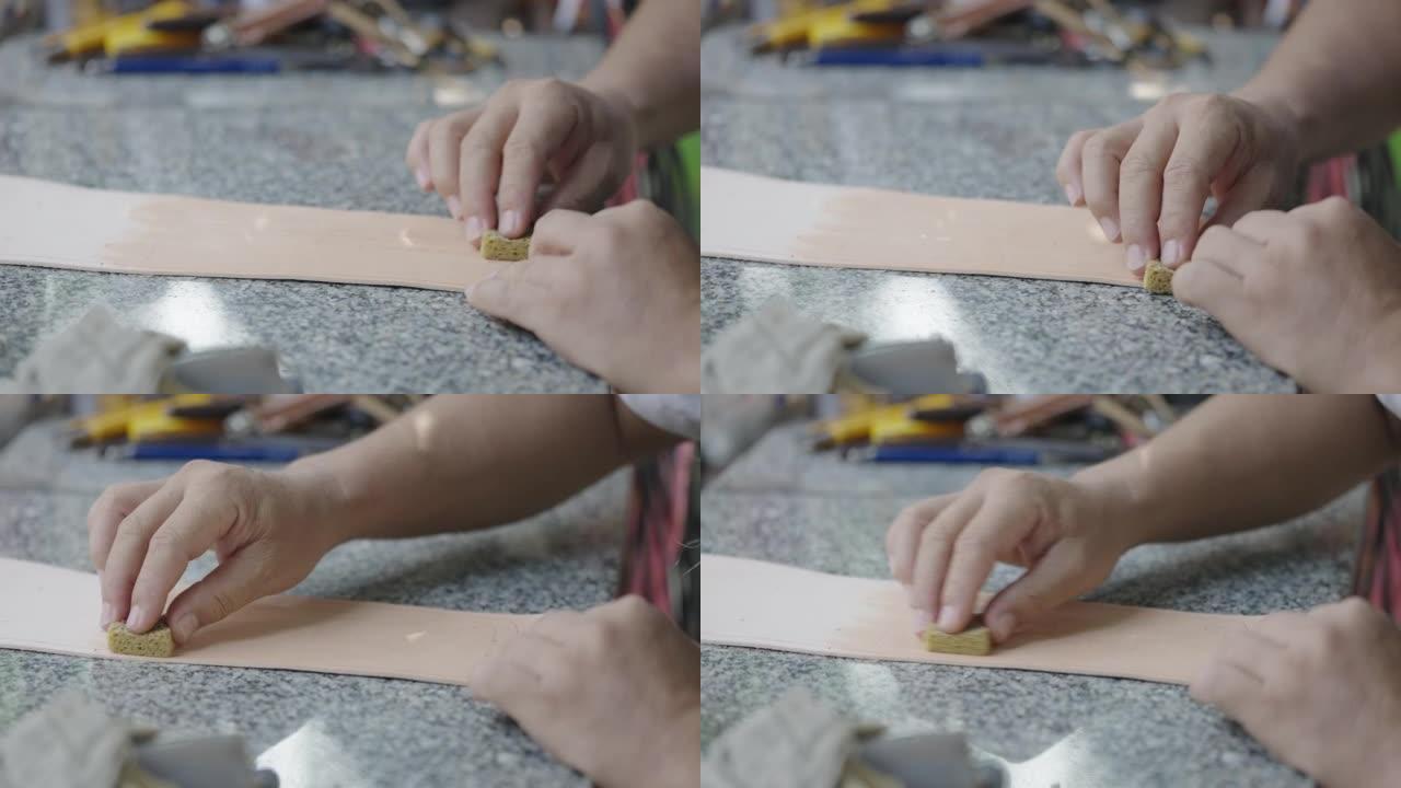 工匠的手在皮革染色中使用海绵。