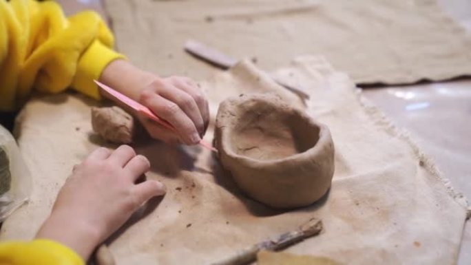 一个穿着黄色衣服的小女孩的手，用粘土雕刻而成。