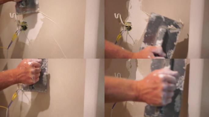 男性建造者使用金属刮铲制作油灰墙，修理工用剥皮膏填充刮铲并覆盖水泥墙面。建筑工人整平墙体和住宅角度改